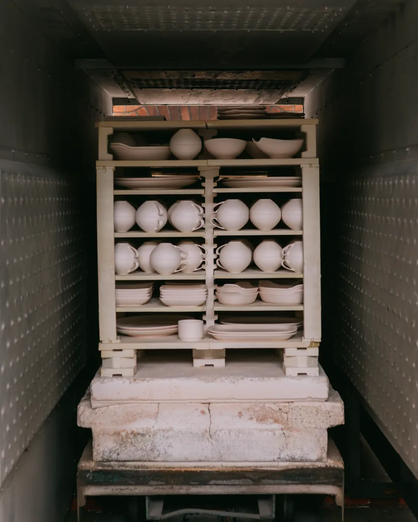 Interior de un horno cerámico cargado con platos y cuencos sin esmaltar apilados sobre placas refractarias